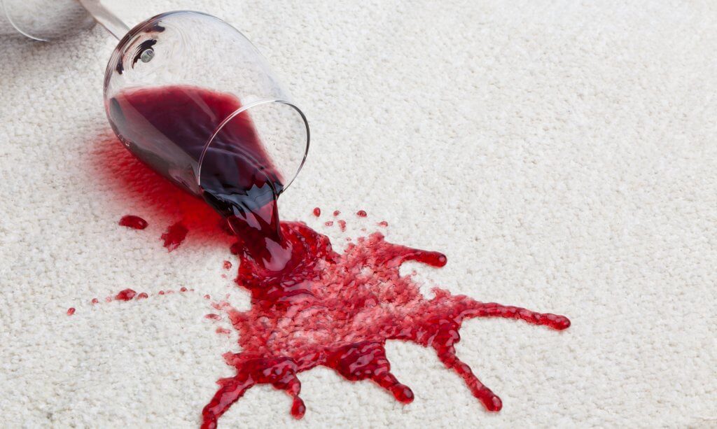 red wine spilling out of a glass onto the carpet