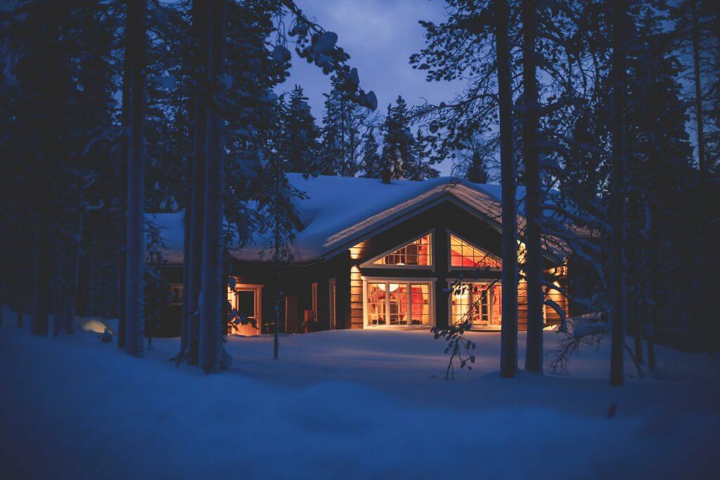 cabin nestled in the woods with snow on the ground